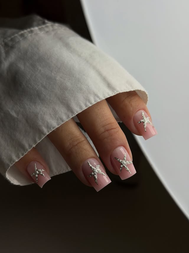 Manicura francesa rosada con estrellas plateadas